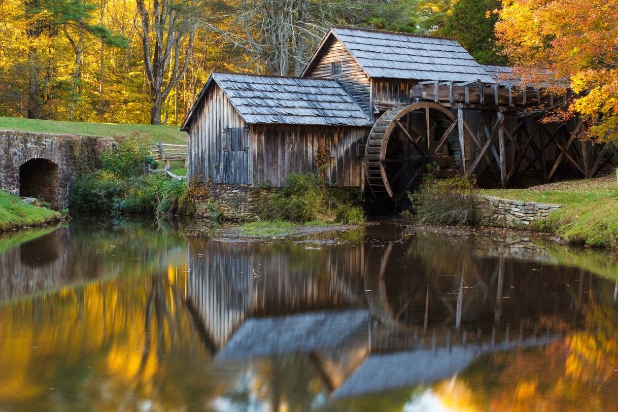 A water mill with two buildings on the side of it.